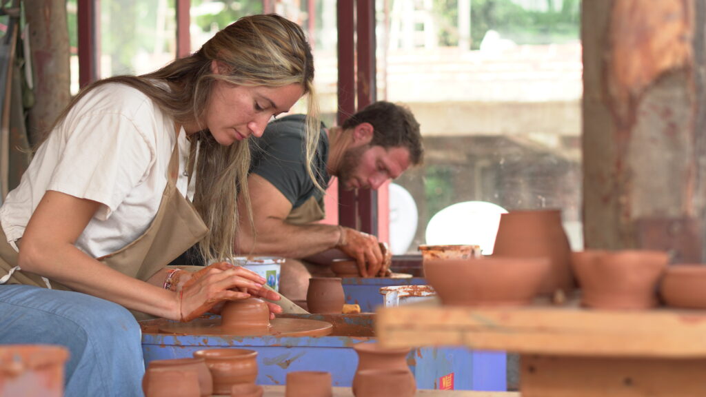 Two guests shaping clay at the wheel